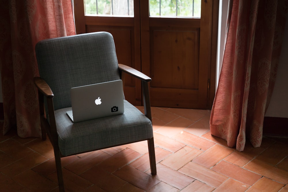 silver MacBook on gray armchair