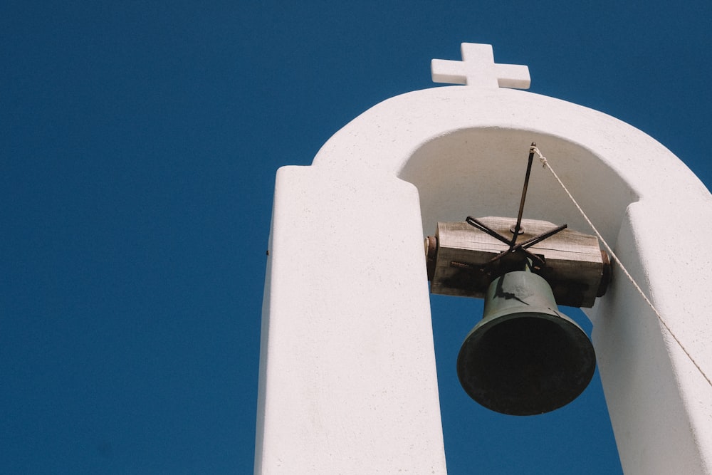 gray bell hanging on white arch