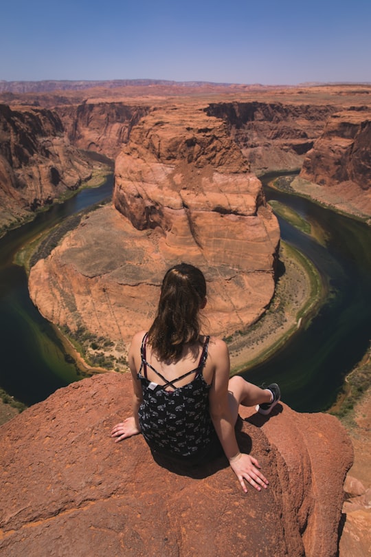 photo of sitting woman in black camisole look down body of water near rocky hills in Arizona United States