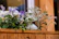 A close-up of a rustic wooden planter filled with vibrant flowers on a backyard porch.