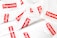 A collection of white plastic bags scattered around, each prominently featuring the red and white Supreme logo. The logo is centered on each bag, creating a repeated pattern throughout the image.