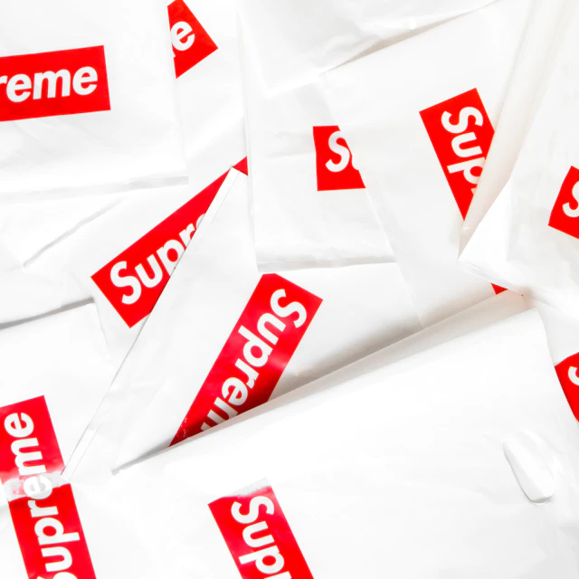A pile of red and white Supreme box logo stickers seen up close