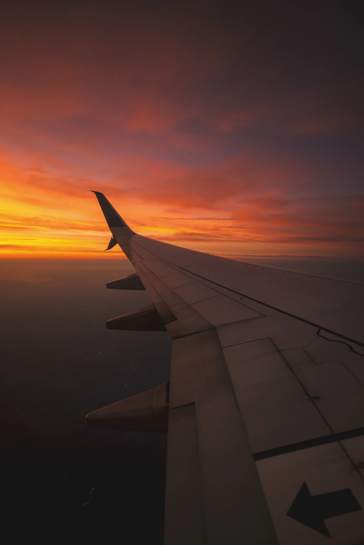 Airplane wing over clouds at sunset