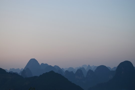 silhouette of mountains under gray sky at daytime in Guangxi China
