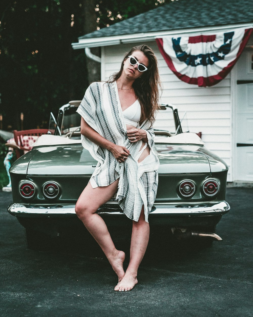 woman standing while leaning on grey car outdoors