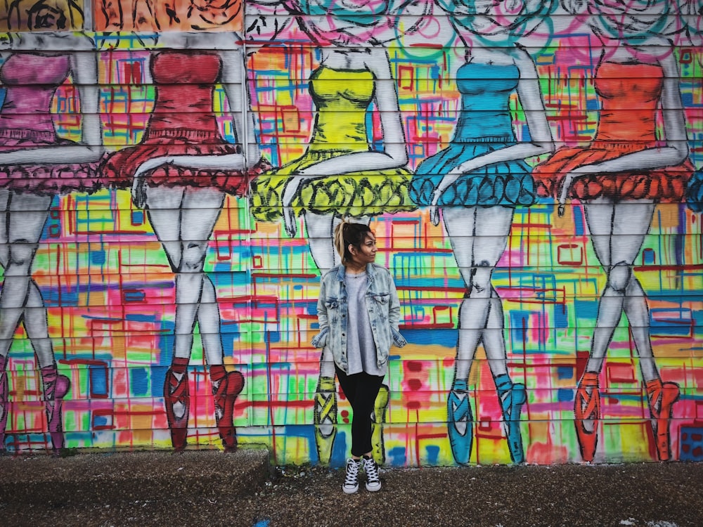 mujer de pie junto al arte de la pared del graffiti