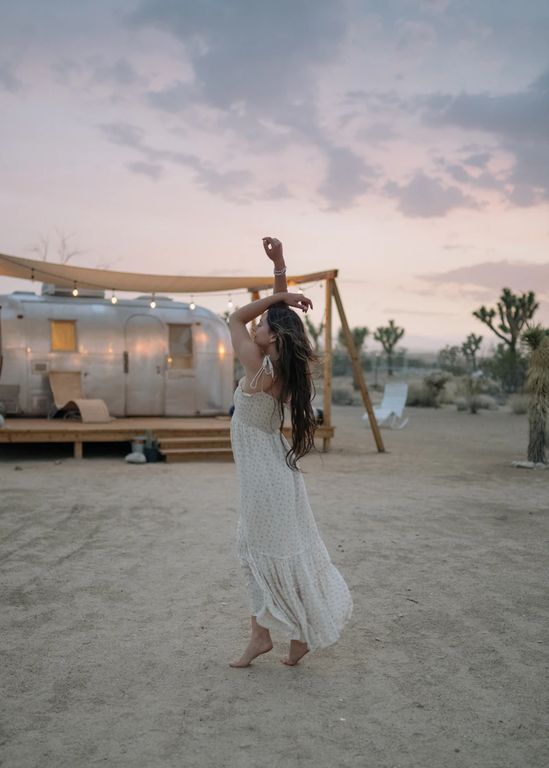 Woman in summer outfit raising her arms — carefree summer style