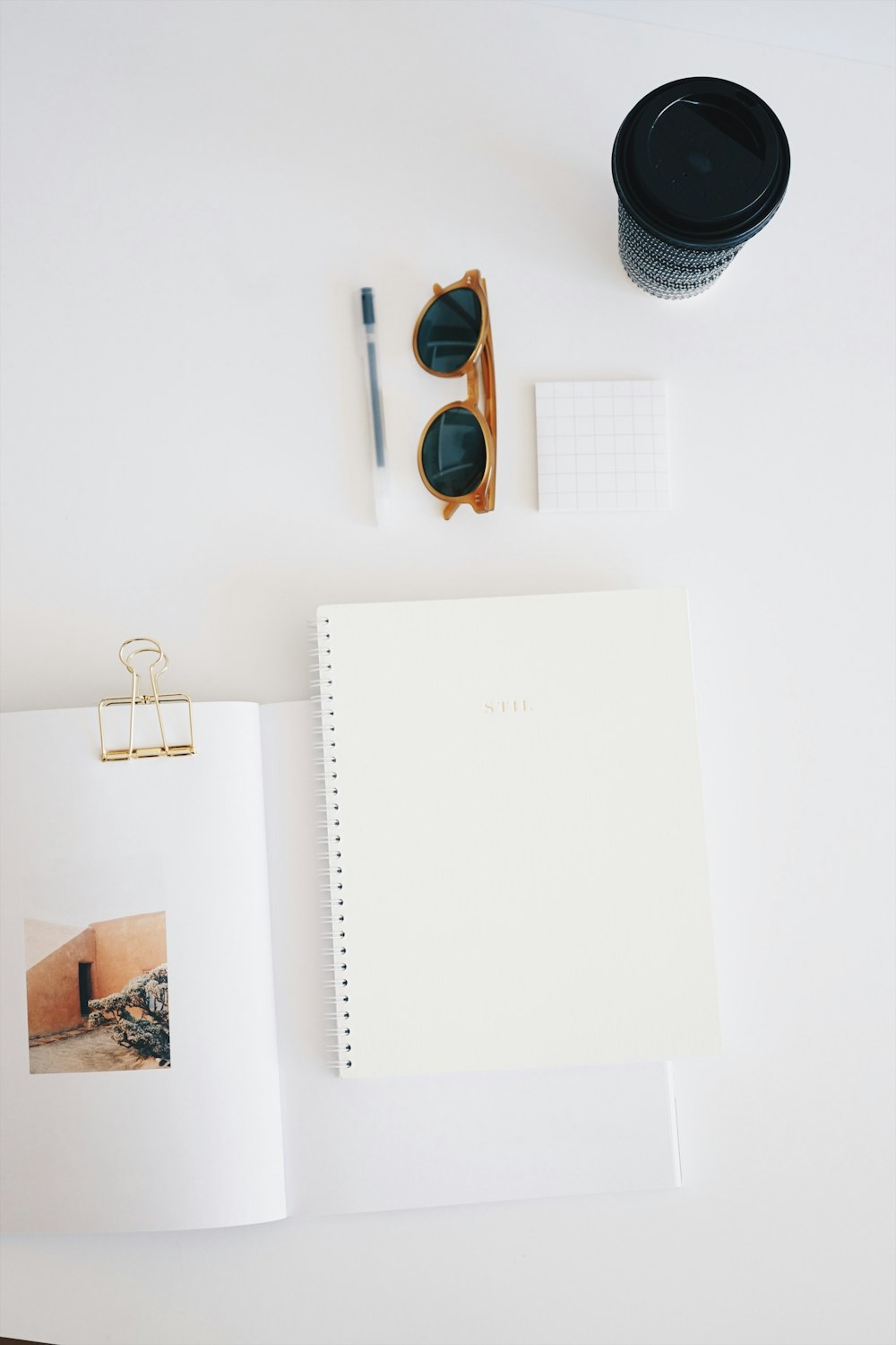 Flat-Lay-Fotografie von Papier, Sonnenbrille, Tasse und Stift