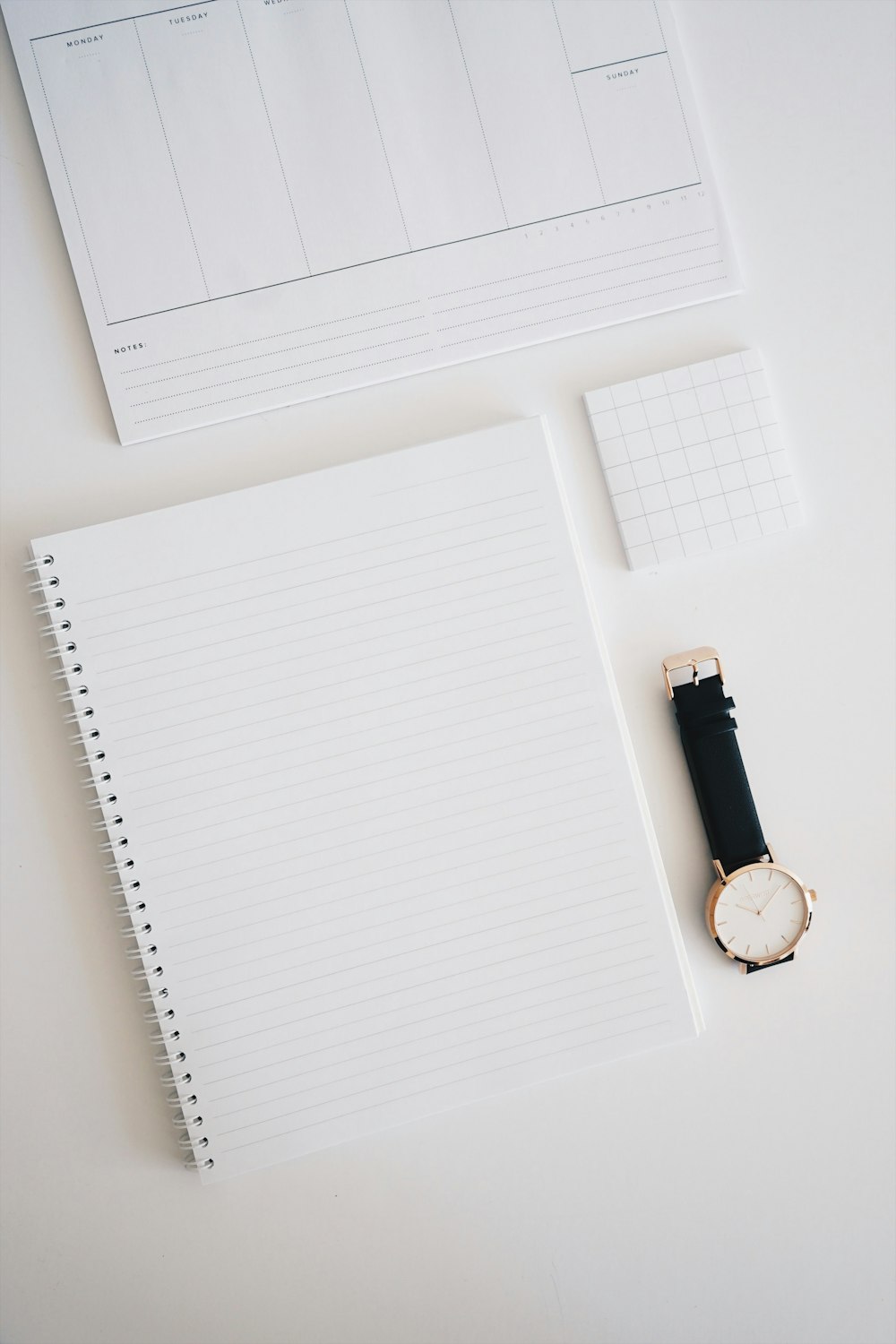 round analog watch with black leather strap on top of white wooden surface