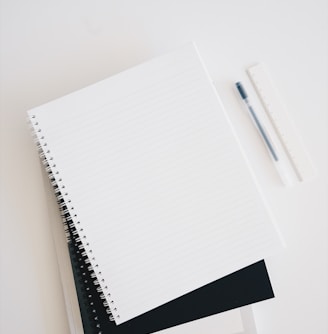 empty spiral notebook near keyboard and pen