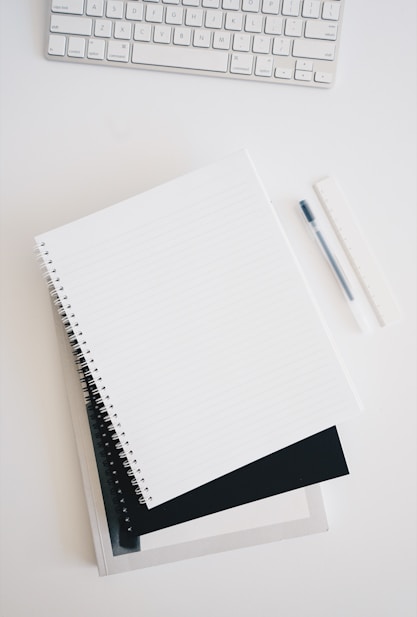 empty spiral notebook near keyboard and pen