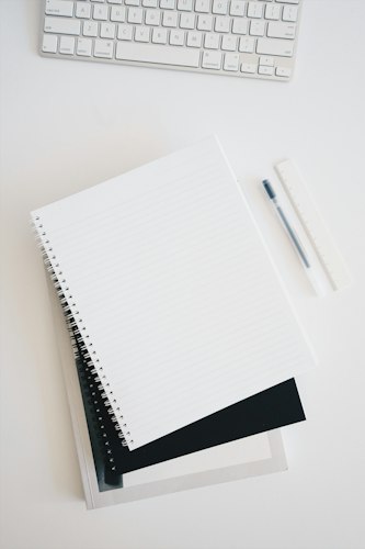 A simple paper planner open on a desk with a pen and a cup of coffee nearby