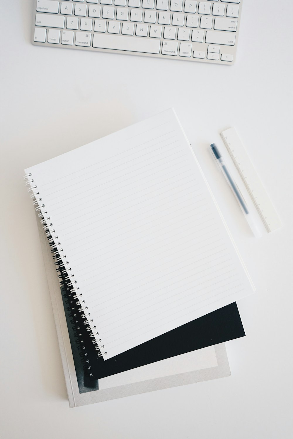 empty spiral notebook near keyboard and pen