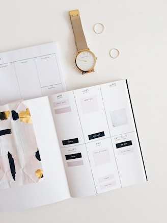 round gold-colored watch beside white brochure