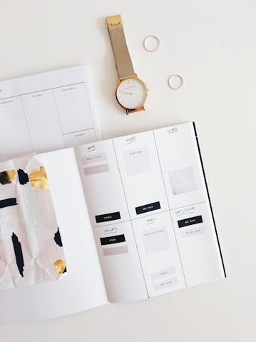 round gold-colored watch beside white brochure