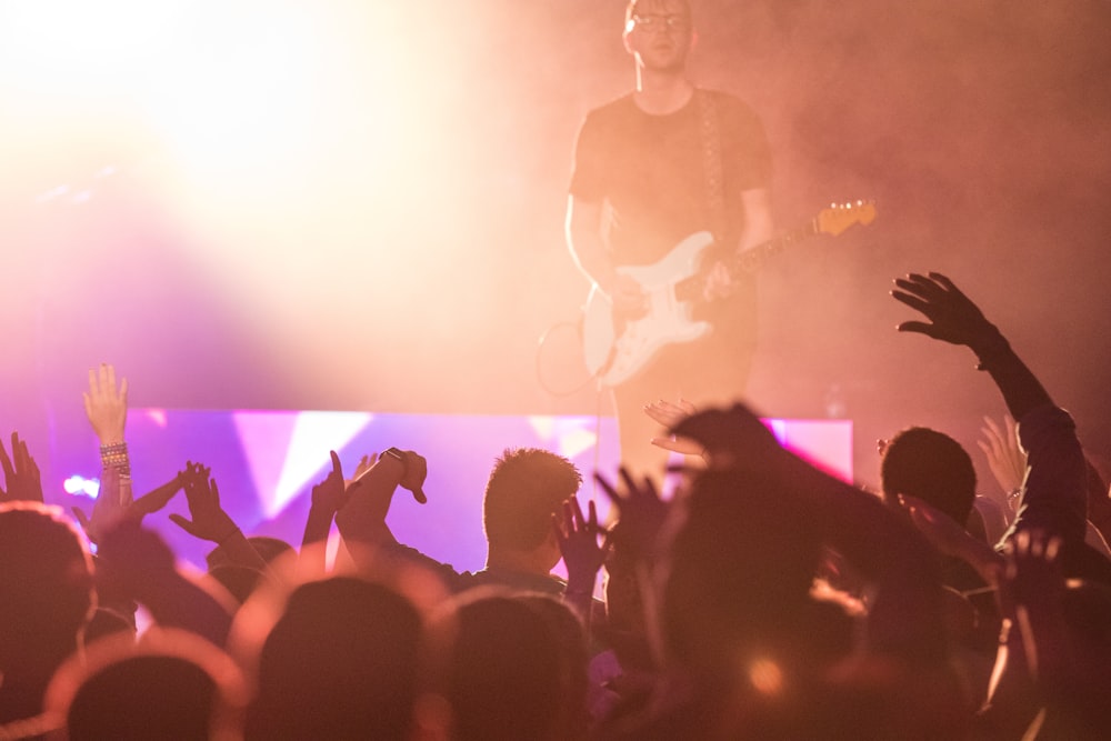 les gens regardent l’homme jouer de la guitare sur scène