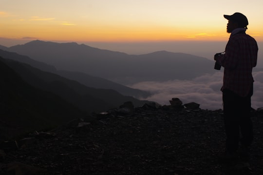 man carrying camera facing sideways looking at the mountain range in Mount Kita Japan