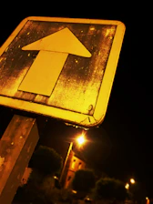 Close-up of a colorful, well-lit road sign at dusk with clear lettering.