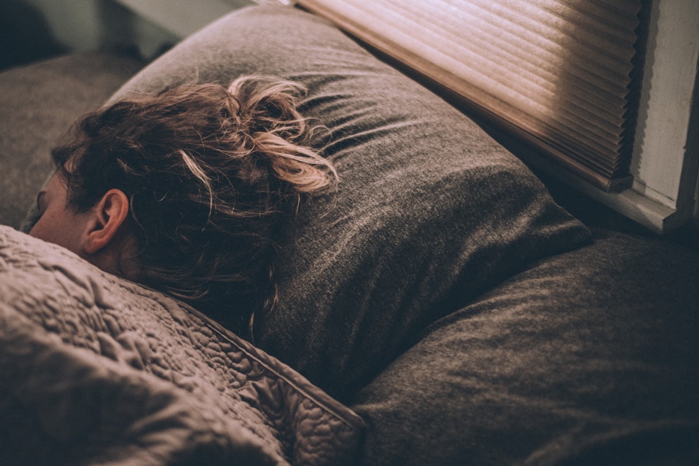 femme dormant sur le lit sous des couvertures