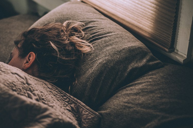 Alarm clock on a nightstand beside a bed with rumpled sheets in early morning light