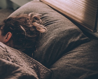 woman sleeping on bed under blankets