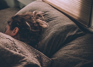 woman sleeping on bed under blankets