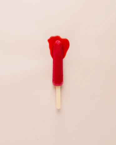 Close-up of a strawberry and mango popsicle melting slightly on a summer day.