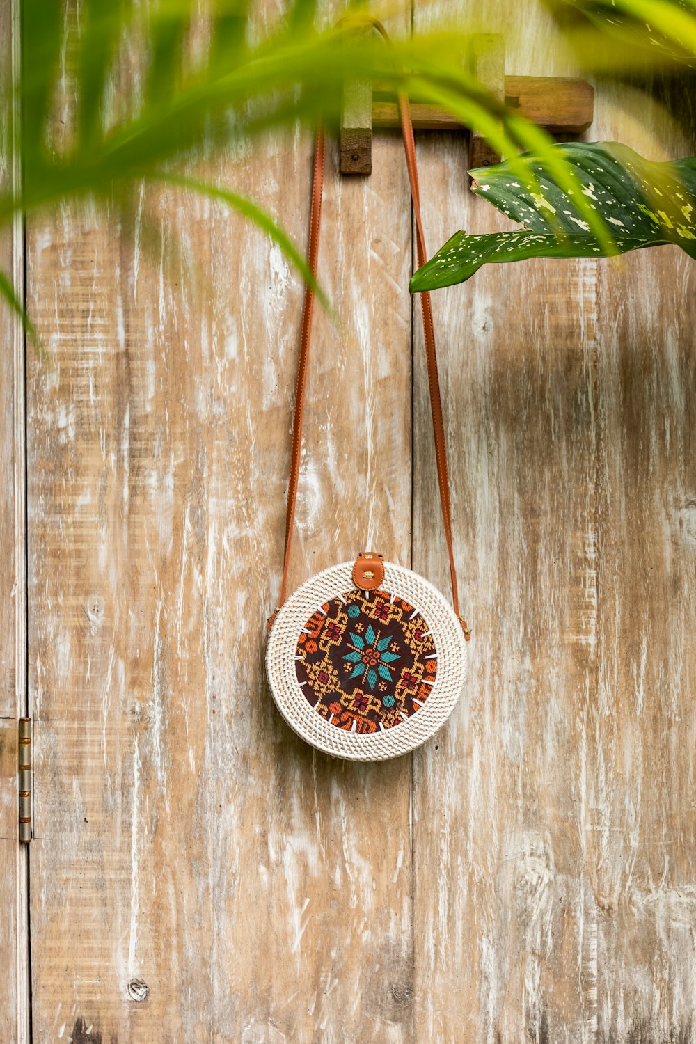 round beige and red floral crossbody bag on brown wooden board