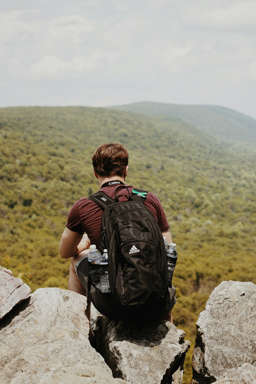 man sitting on rock with backpack