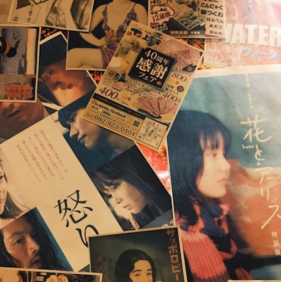 A collage of various posters and flyers, some featuring portraits of people in different poses and expressions, likely from movies or promotional events. The text on the materials appears to be in Japanese, with colorful and diverse visuals.