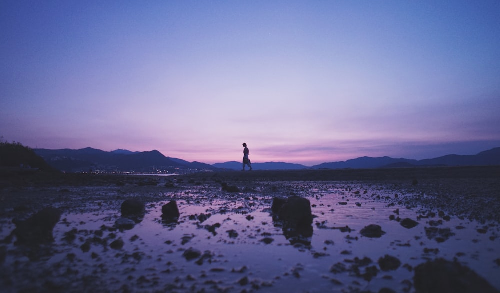 person walking on rocky sand