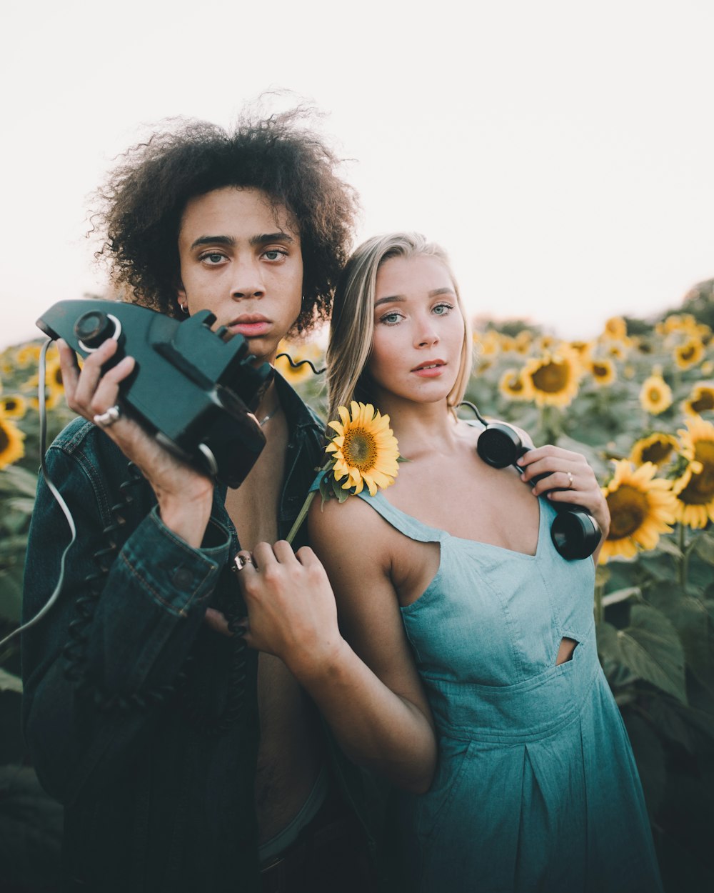 man holding corded device standing beside woman wearing blue dress