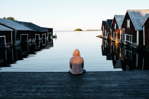 person sitting beside body of water