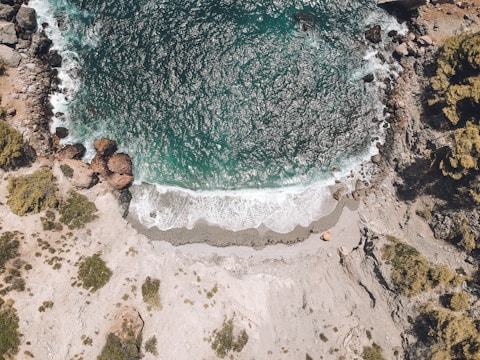 Scenic view of a secluded beach surrounded by green cliffs and calm sea.