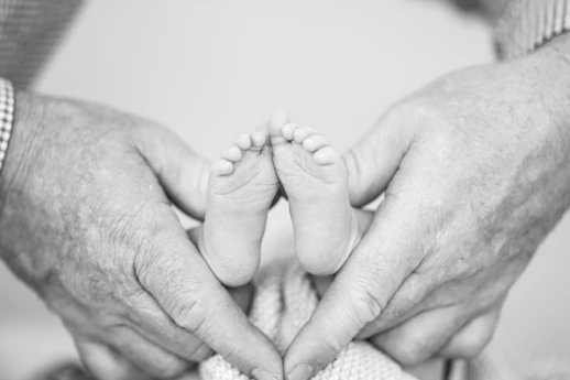 grayscale photography of person holding newborn's feet