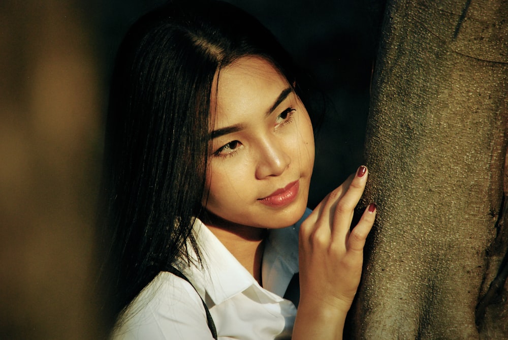 woman in white shirt near tree trunk