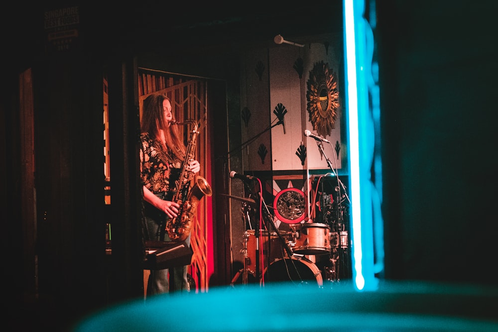 벽시계 근처 무대에서 색소폰을 연주하는 여자