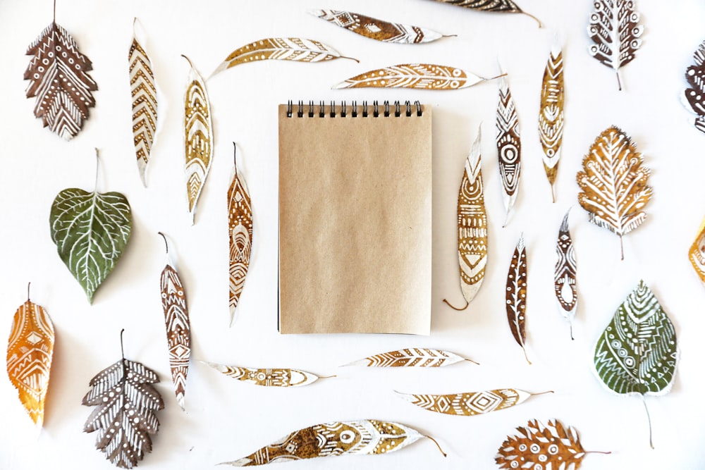 flat lay photography of tribal leaves and steno notebook