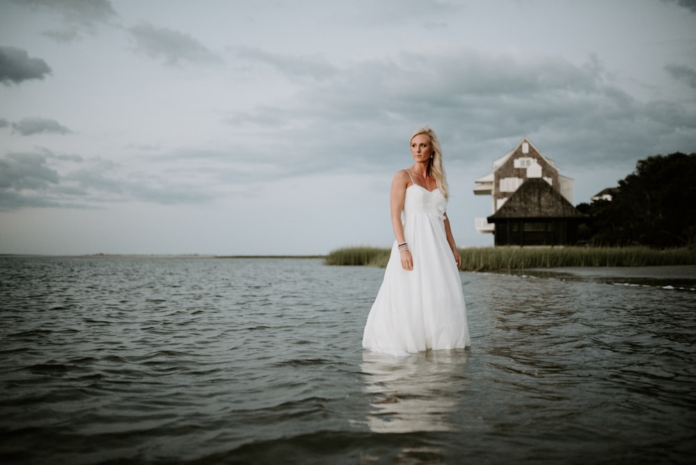 woman wearing white spaghetti strap dress above of body of water