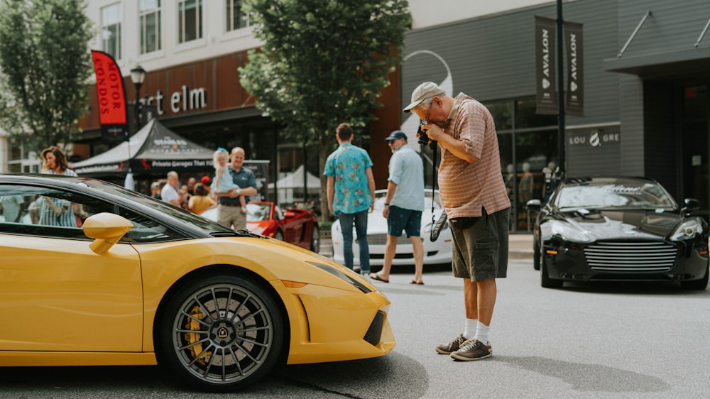 hombre de pie frente a un auto deportivo amarillo