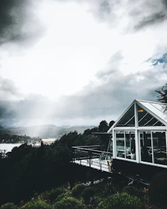 A modern house with large windows overlooking lush green mountains and a distant view of the sea.