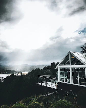 A modern house with large windows overlooking lush green mountains and a distant view of the sea.