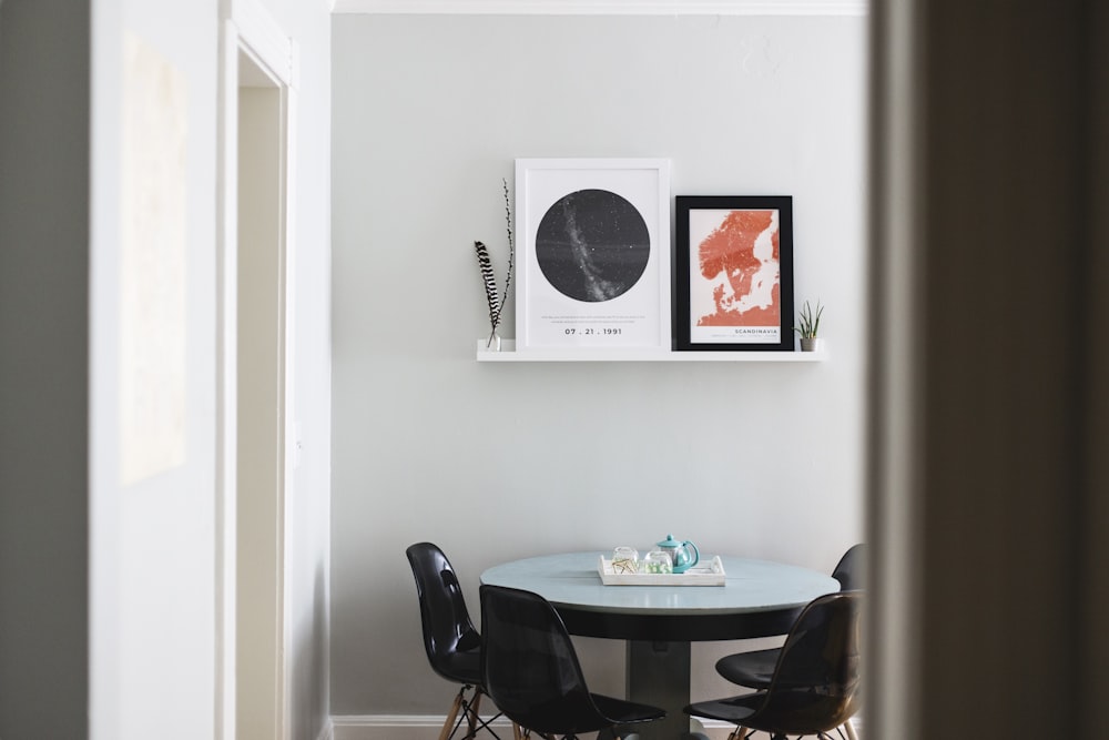 table with four chairs under two posters on wall
