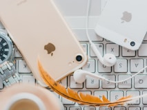 gold iPhone 7 beside white Apple EarPods and silver iPhone 5s