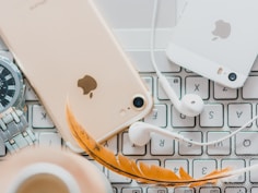 gold iPhone 7 beside white Apple EarPods and silver iPhone 5s