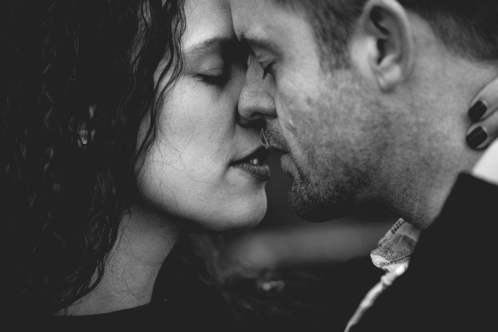 grayscale photo of man and woman kissing each other