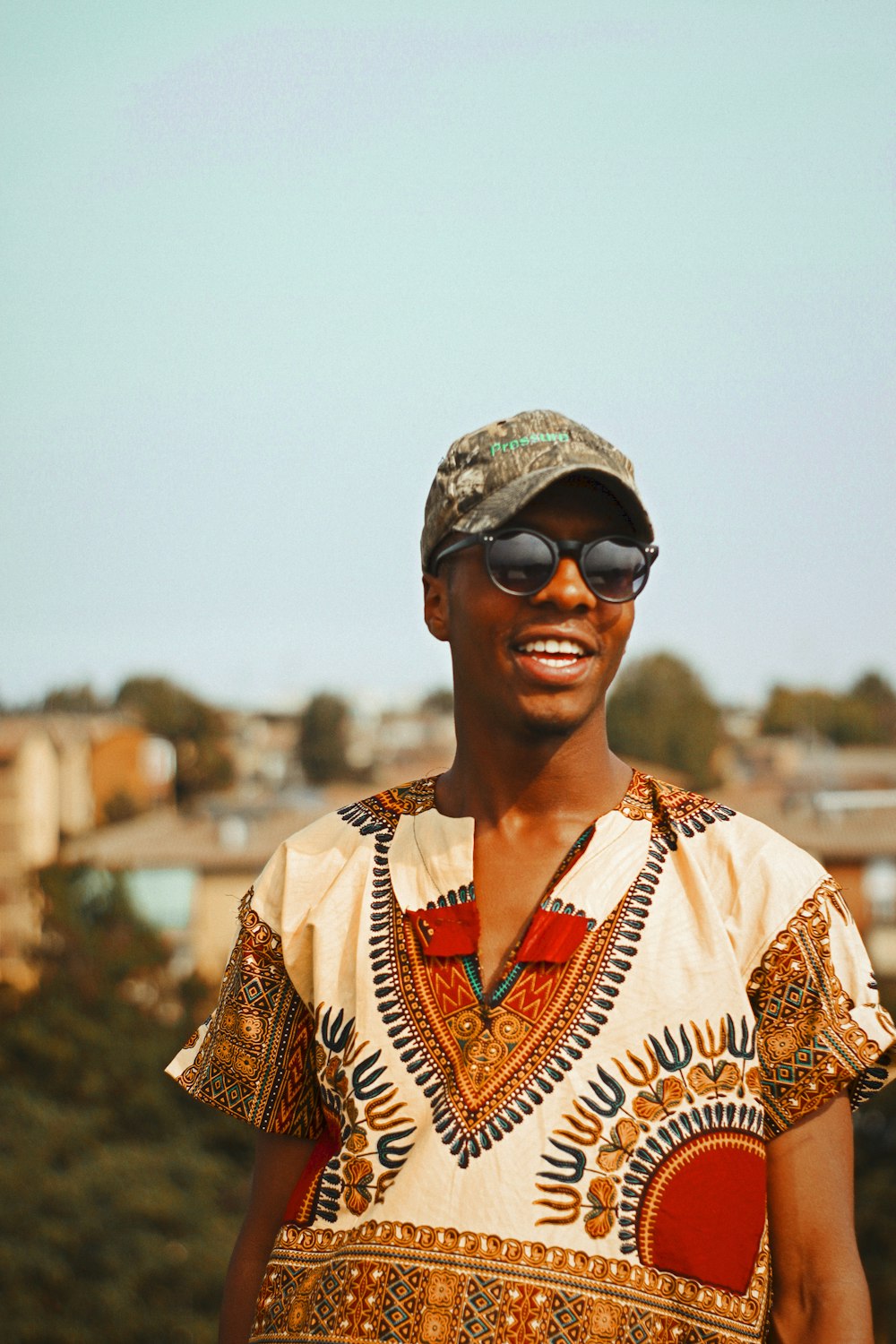 smiling man wearing brown baseball cap under clear sky