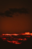 A wide-angle cinematic landscape with dramatic skies and deep red hues.