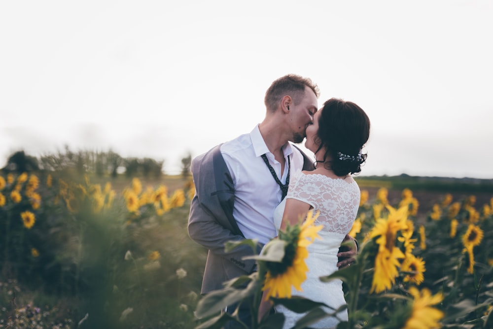 man and woman kissing in middle of sunflower field