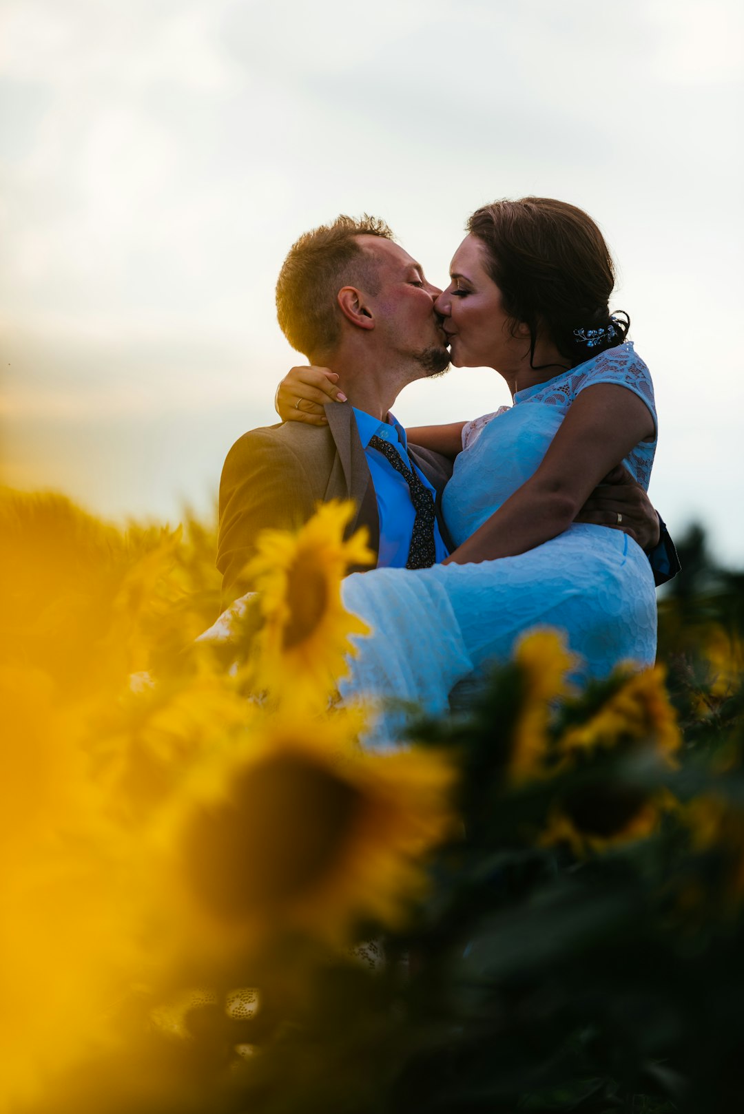 couple kissing in sunflower garden